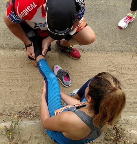 Medical responder treating injured runner’s leg Medical responder treating injured runner's leg
