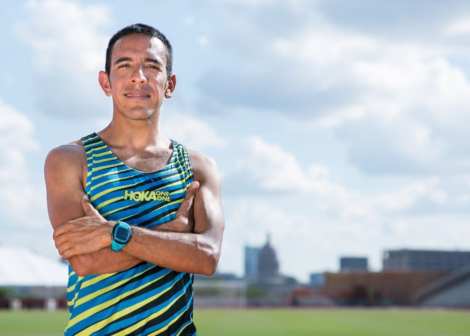 Male runner in striped Hoka singlet on track Male runner in striped Hoka singlet on track