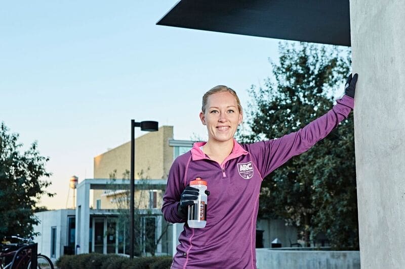 Athletic woman in purple jacket holding water bottle