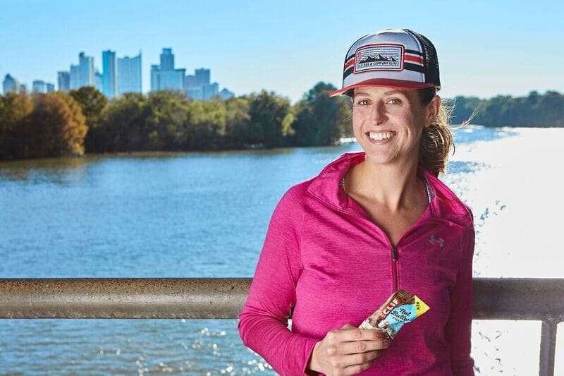 Smiling woman in pink jacket holding snack