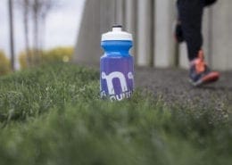 Blue water bottle on grass beside runner