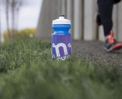 Blue water bottle on grass beside runner