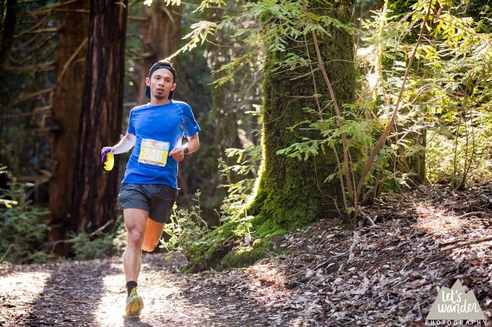 Runner in blue shirt on wooded trail