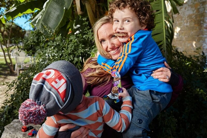 Smiling woman hugging two children outdoors Smiling woman hugging two children outdoors