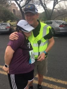Runner hugging volunteer in high-visibility vest