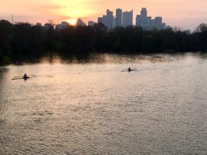 Rowers on river at sunset with skyline