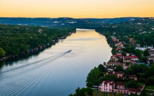 Boat creating wake on river by homes