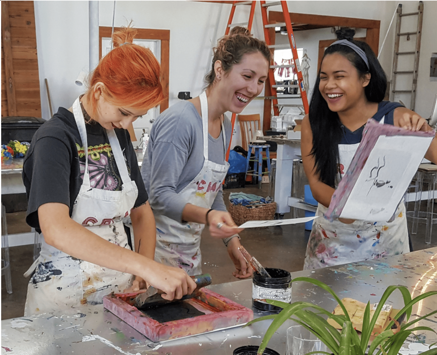 Three women laughing while screen printing Three women laughing while screen printing