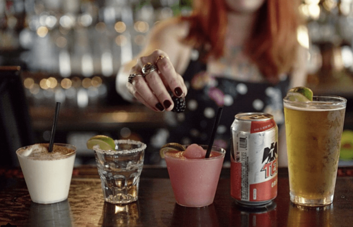 Hand reaching for assorted drinks on bar Hand reaching for assorted drinks on bar