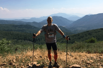 Person with trekking poles on mountain ridge