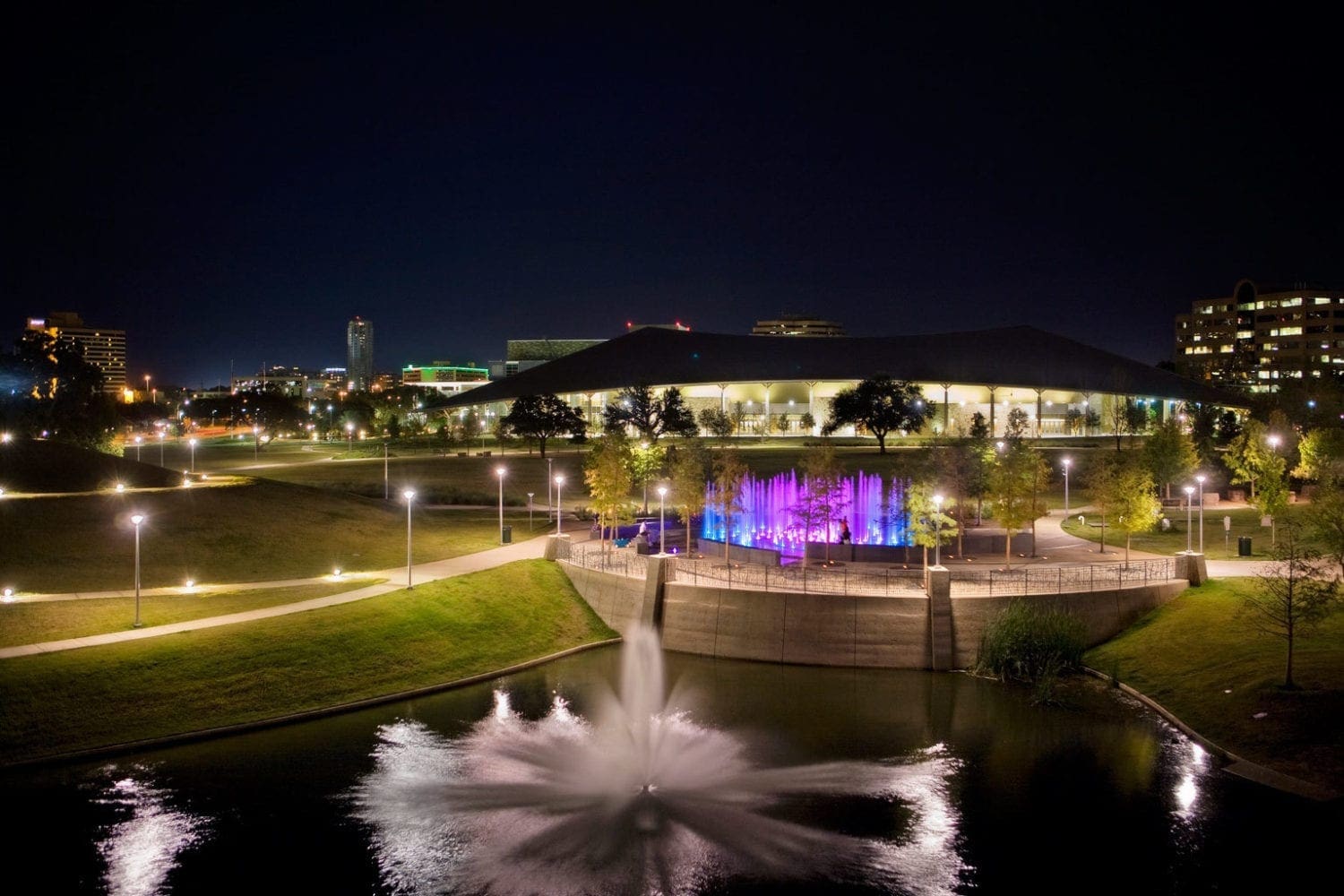 Nighttime park with illuminated purple fountain
