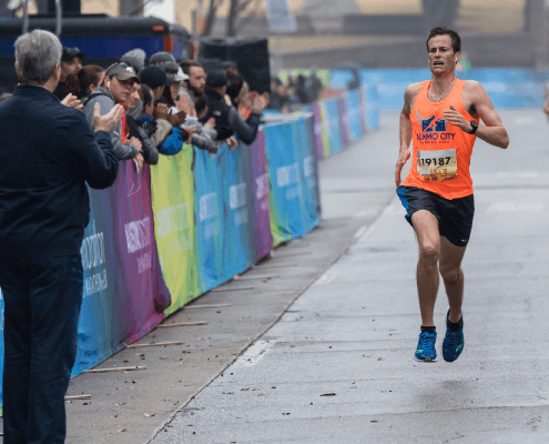 Runner in orange passing cheering spectators