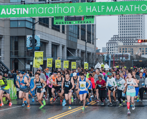 Runners starting Austin marathon under green banner