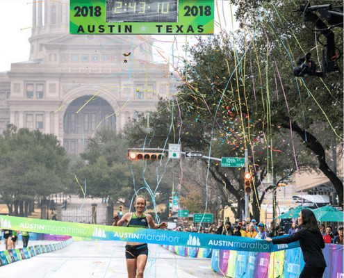 Runner crossing Austin Marathon finish line with confetti