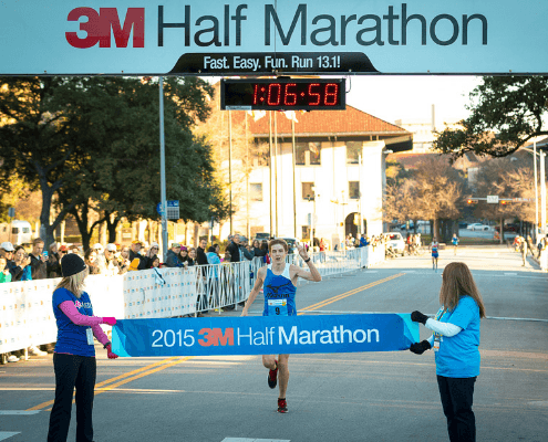 Runner crossing 3M Half Marathon finish line