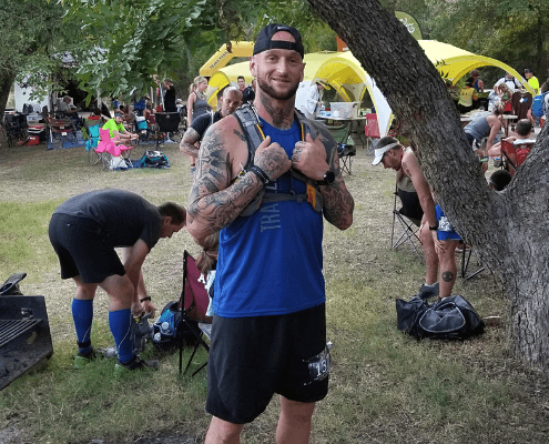 Tattooed man giving thumbs up at outdoor event