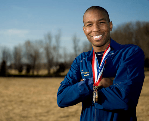 Smiling athlete outdoors wearing medals and blue jacket