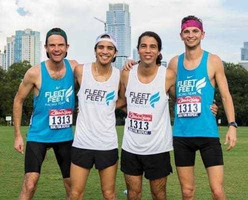 Four runners smiling in Fleet Feet shirts