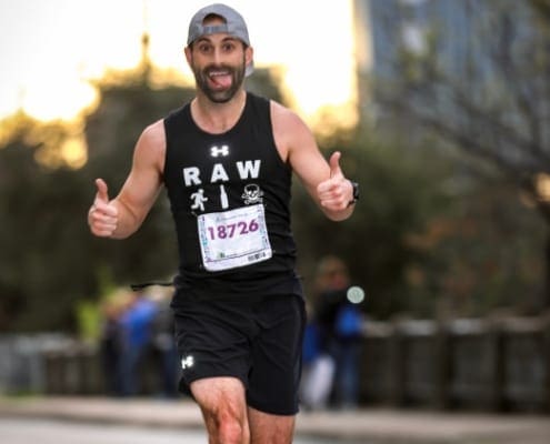 Smiling male runner giving thumbs-up during race