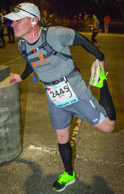 Runner stretching leg before night road race