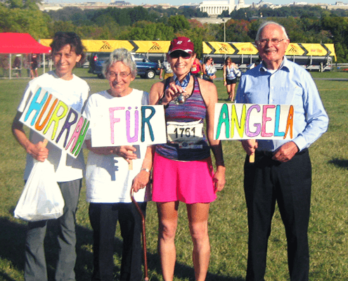 Four people holding colorful "Hurrah for Angela" signs