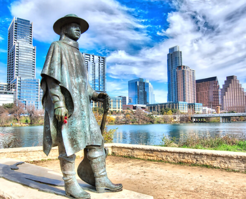 Bronze guitarist statue by downtown skyline and lake