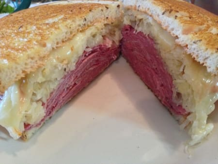 Image of a sandwich from New World Deli stacked high with meat and cheese. New World Deli is one of 5 Austin restaurants along the Austin Marathon course that people should visit.