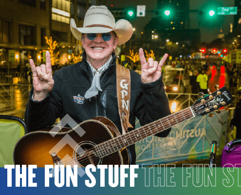 Smiling guitarist in cowboy hat at nighttime festival