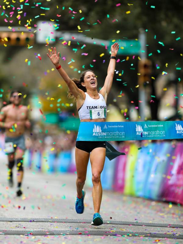 Marathon runner crossing finish line amid confetti Marathon runner crossing finish line amid confetti
