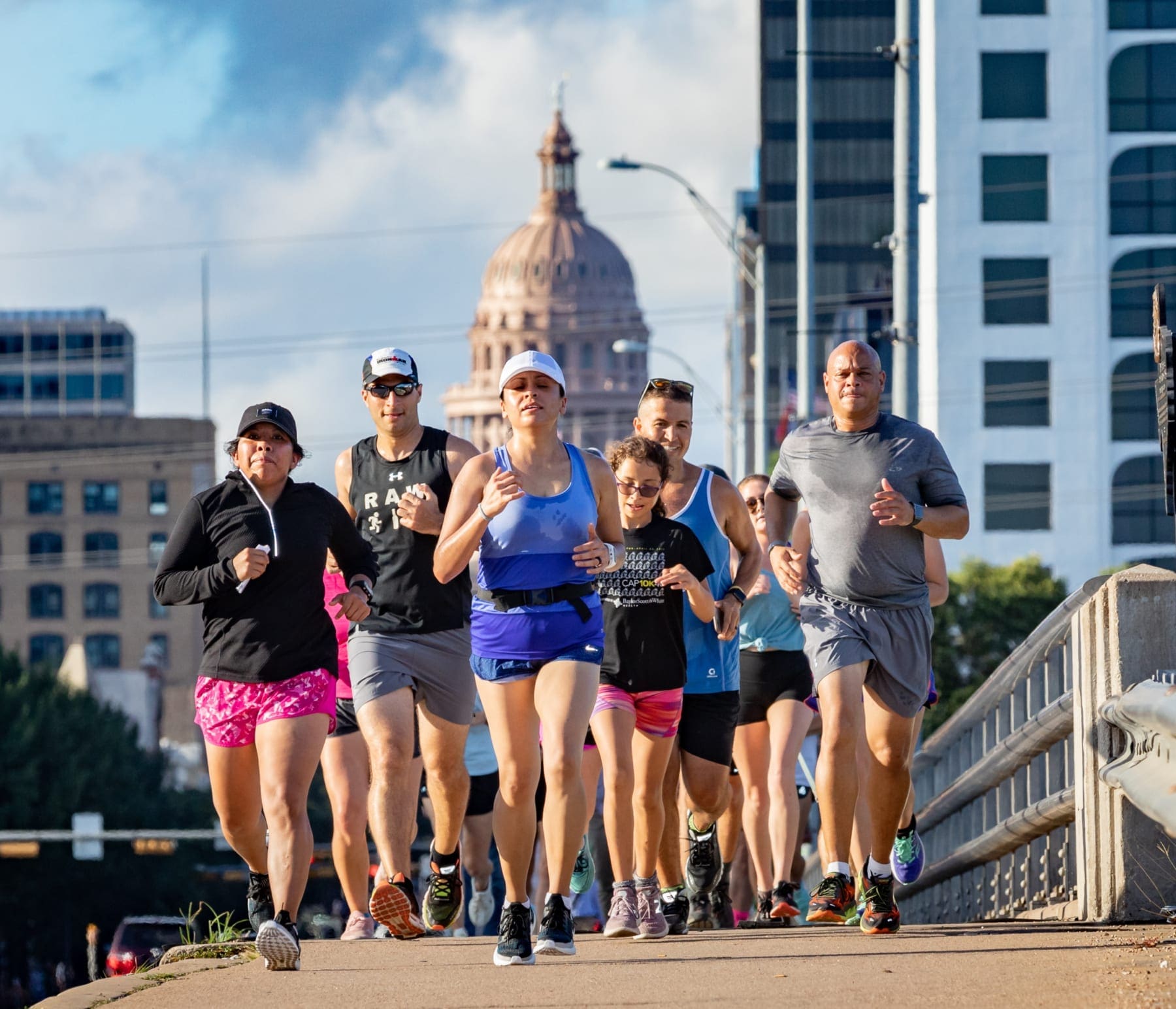Image of runners running during the 2019 free Global Running Day event on the Congress Avenue Bridge in Austin with the Texas State Capitol in the background.
