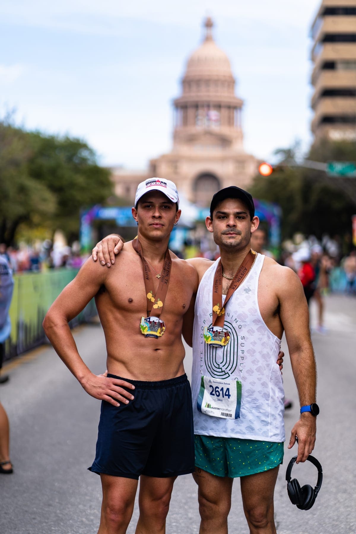 Two runners posing with medals near state capitol