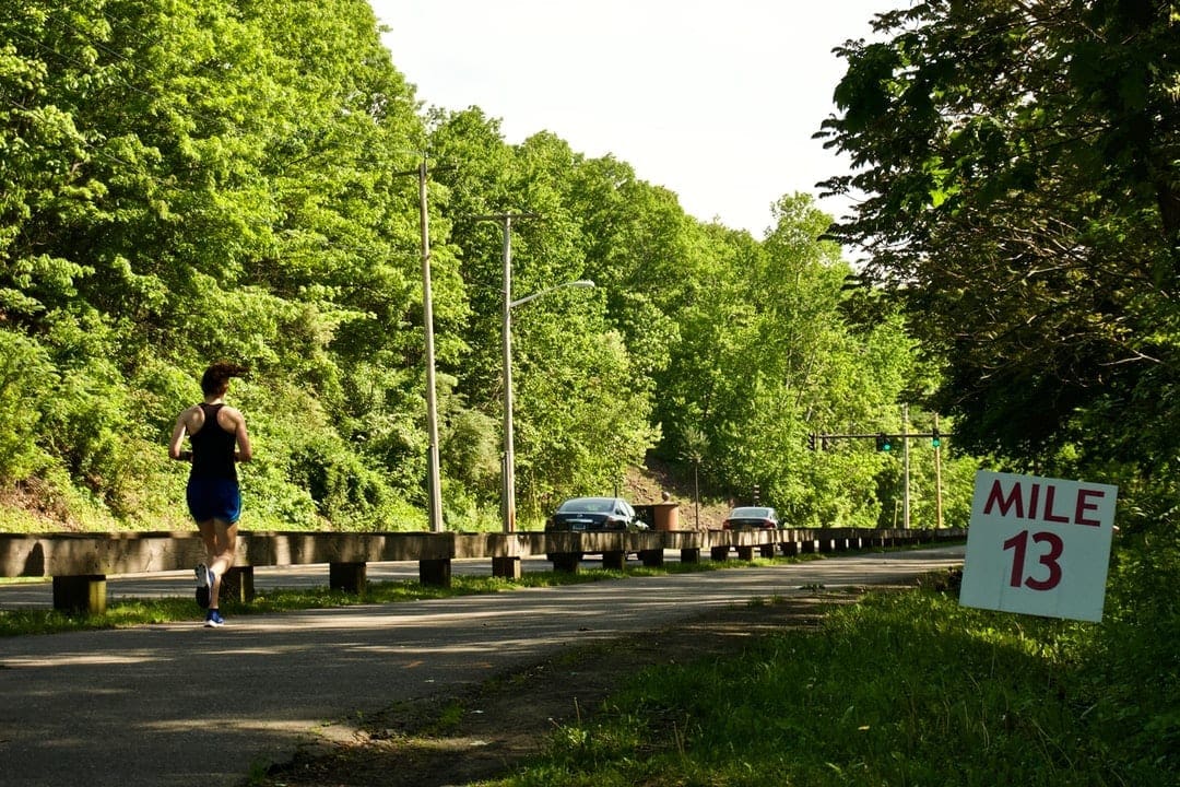 Runner passing Mile 13 sign on road