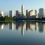 City skyline reflected on calm lake at sunrise