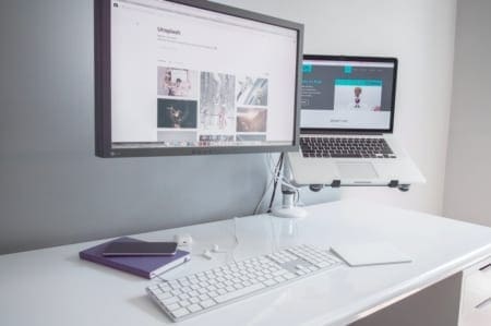Minimal white desk with monitor and laptop