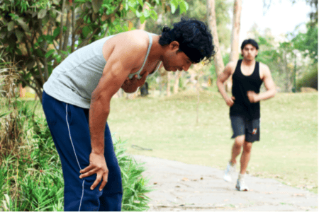 Two men exercising outdoors, one bent over