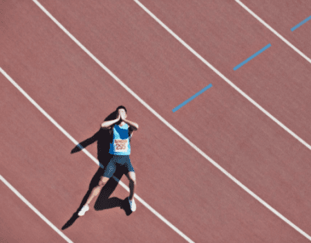 Athlete lying on track lane covering face