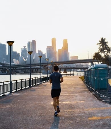 Jogger on waterfront path with city skyline