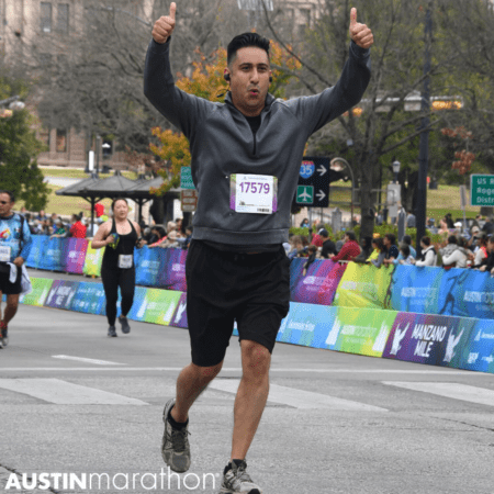 Male runner crossing Austin Marathon finish line