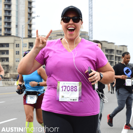 Smiling Austin Marathon runner flashing rock sign