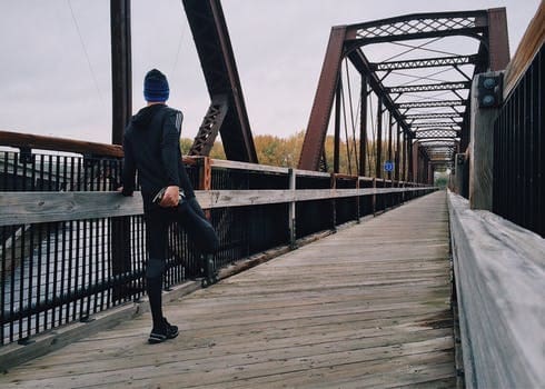 Runner stretching on wooden truss bridge