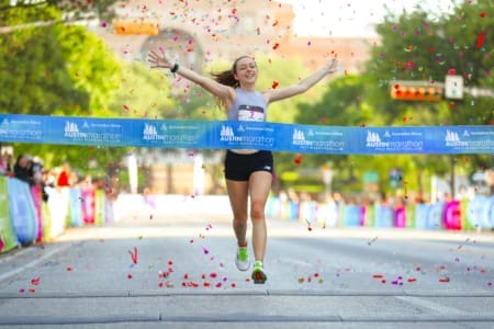 Runner crossing marathon finish line with confetti