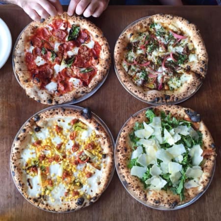 Four artisanal pizzas on wooden table