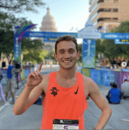 Smiling runner in orange tank top at finish Smiling runner in orange tank top at finish