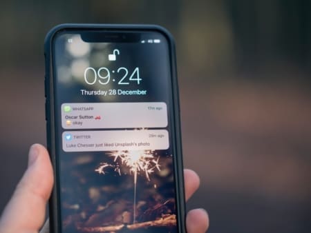 Hand holding smartphone with sparkler wallpaper