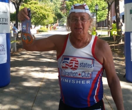 Marathon finisher holding medal at finish line Marathon finisher holding medal at finish line