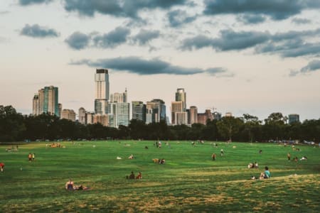 People relaxing in large park with city skyline People relaxing in large park with city skyline
