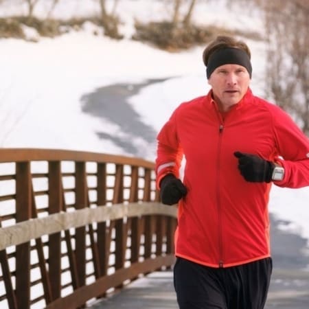 Runner in red jacket on snowy bridge