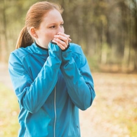 Woman warming hands in blue jacket outdoors