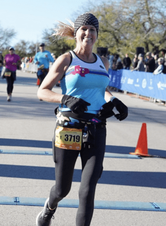 Smiling female runner crossing race finish mat