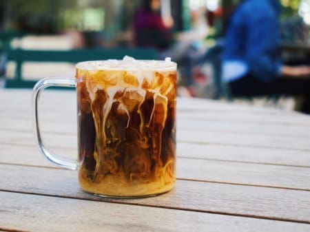 Iced coffee with cream swirling in glass